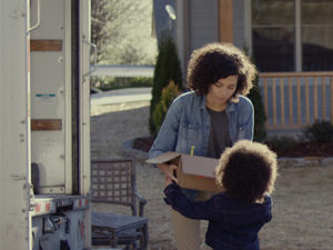 Mother passing her child a box off of a moving truck