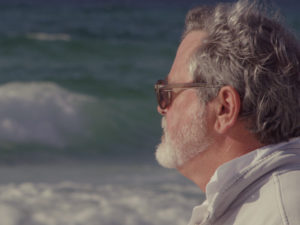 Gray haired man looking off into the ocean