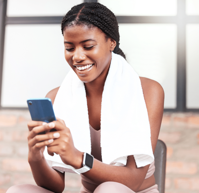 Woman sitting at the gym and checking her online banking with her cell phone