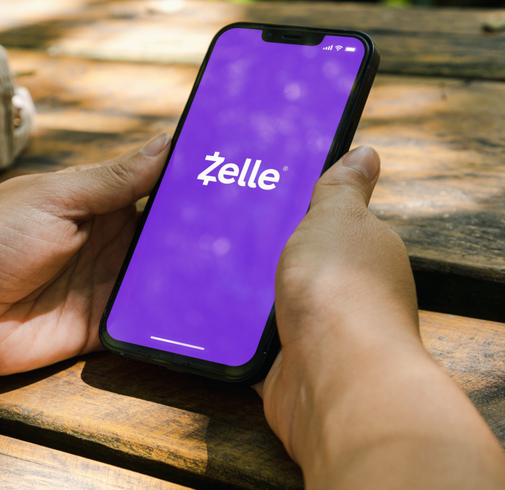 A close-up shot of a person holding their phone, the Zelle app is on their screen.