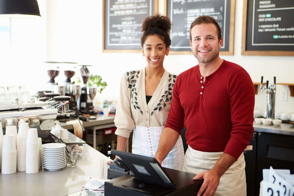 A man and a woman behind a coffee bar.