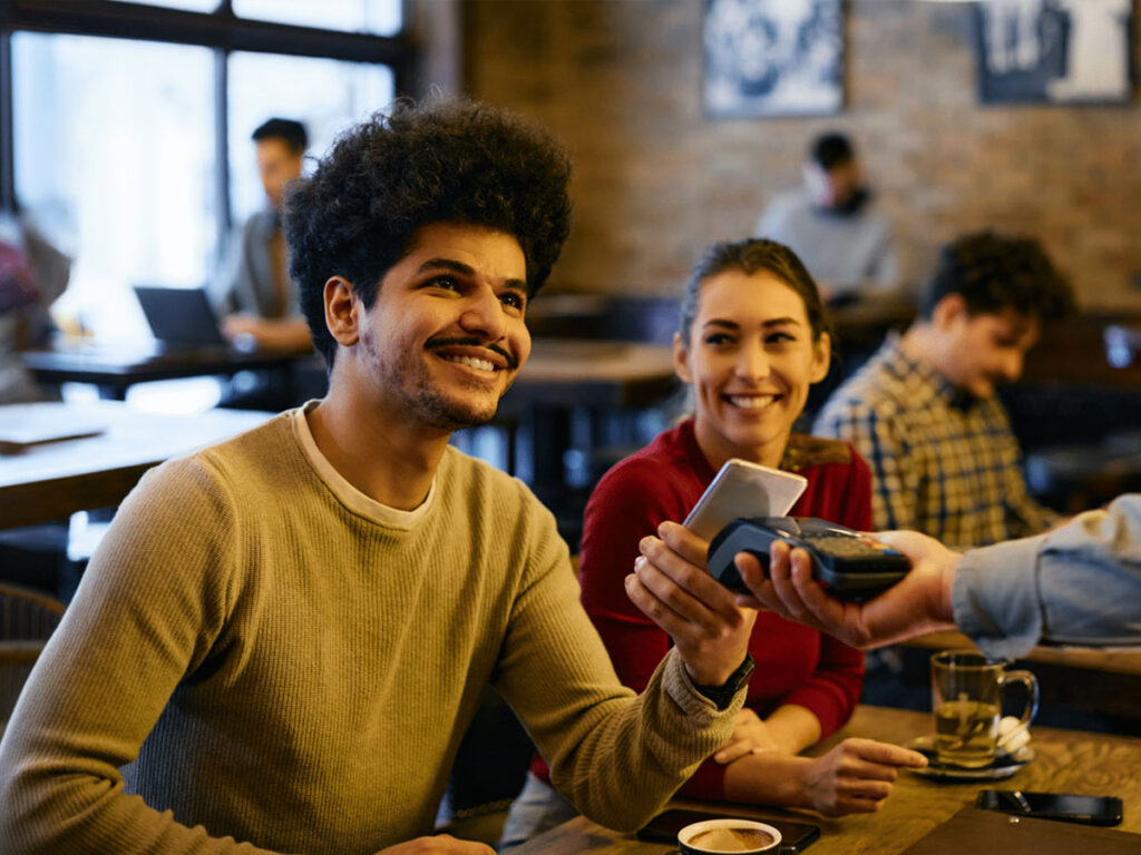 Young man paying for a meal with a contactless payment system.